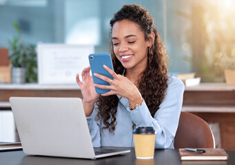 Poster - Let me send them an update. Cropped shot of an attractive young businesswoman sending a text while working on a laptop at her desk in the office.