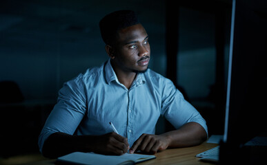 Aufkleber - You cant finish a task without a bit of focus. Shot of a young businessman writing in a notebook and using a computer during a late night at work.