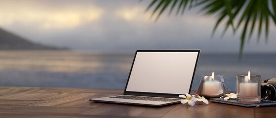 Wall Mural - Laptop, aroma candles on wood table against blurred sea view. Travel and remote working