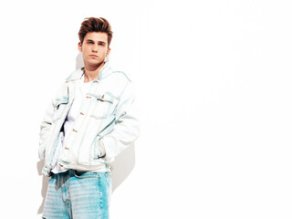 Portrait of handsome confident stylish hipster lambersexual model.Man dressed in jacket and jeans. Fashion male posing in studio near white wall. Isolated