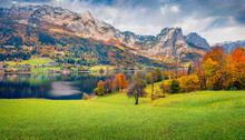 Dramatic Autumn Scenery. Colorful Autumn View Of Grundlsee Lake With Huge Mountain Range On Background. Nice Morning Scene Of Brauhof Village, Styria Stare Of Austria, Europe.