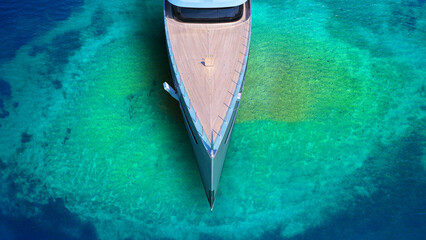 Aerial drone top down photo of luxury exotic yacht nose with wooden deck anchored in paradise turquoise bay