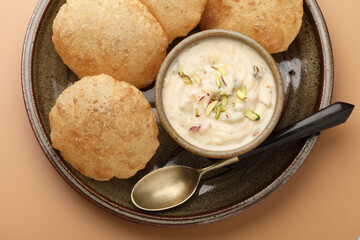 Wall Mural - Shrikhand & Puri, Shrikhand is an Indian sweet dish made of strained curd,garnished with dry fruits and saffron. Served in a ceramic bowl & plate with Puri, Deep fried flat bread.Selective focus