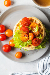 Wall Mural - Stack of savory waffles with cherry tomatoes and lettuce, top view, gray background, breakfast concept.