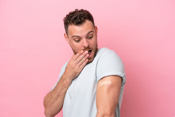 Wall Mural - Young Brazilian man wearing a band-aids isolated on pink background with surprise and shocked facial expression