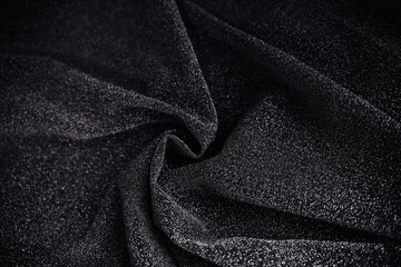 Black wrinkled fabric with sequins.Draped material. Glowing texture. Night sky