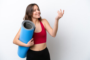 Young sport caucasian woman going to yoga classes while holding a mat isolated on white background extending hands to the side for inviting to come