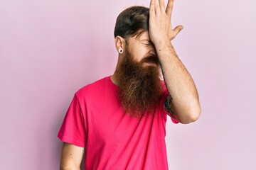 Canvas Print - Redhead man with long beard wearing casual pink t shirt surprised with hand on head for mistake, remember error. forgot, bad memory concept.