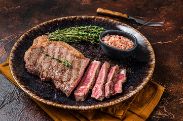 Sticker - BBQ roast sliced New York  beef steak on a plate with thyme and salt. Dark background. Top view