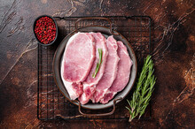 Raw Pork Chop Steaks In Steel Tray With Rosemary. Dark Background. Top View