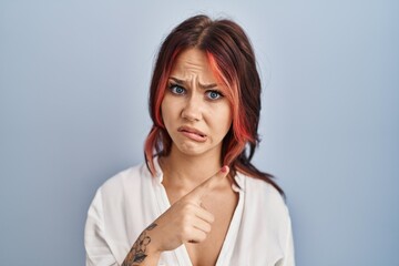 Sticker - Young caucasian woman wearing casual white shirt over isolated background pointing aside worried and nervous with forefinger, concerned and surprised expression