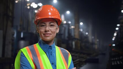 Wall Mural - woman engineer smiling camera wearing safety helmet at huge industrial storage.