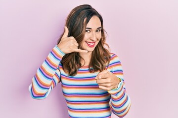 Poster - Young hispanic girl wearing casual clothes smiling doing talking on the telephone gesture and pointing to you. call me.