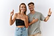 © Krakenimages.com - Young beautiful couple standing together over isolated background smiling swearing with hand on chest and fingers up, making a loyalty promise oath