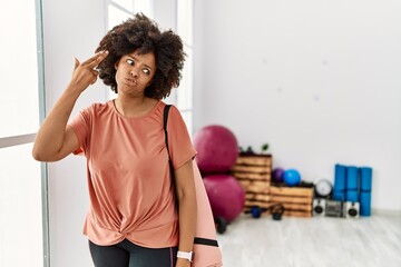 Sticker - African american woman with afro hair holding yoga mat at pilates room shooting and killing oneself pointing hand and fingers to head like gun, suicide gesture.