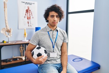 Wall Mural - Hispanic man with curly hair working as football physiotherapist depressed and worry for distress, crying angry and afraid. sad expression.