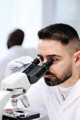 Aufkleber - Young male worker of contemporary scientific laboratory using microscope during research of new virus or bacteria