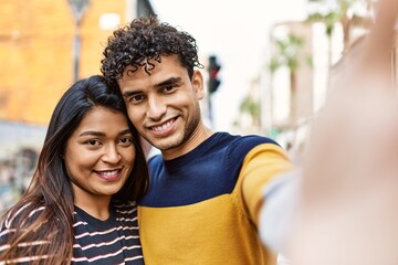 Poster - Young latin couple smiling happy and hugging make selfie by the camera at the city.