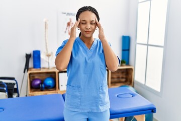 Wall Mural - Young african american woman working at pain recovery clinic with hand on head for pain in head because stress. suffering migraine.