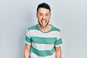 Canvas Print - Young hispanic man wearing casual clothes sticking tongue out happy with funny expression. emotion concept.