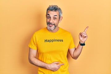 Canvas Print - Handsome middle age man with grey hair wearing t shirt with happiness word message smiling happy pointing with hand and finger to the side