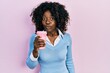 © Krakenimages.com - Young african american woman drinking take away coffee scared and amazed with open mouth for surprise, disbelief face