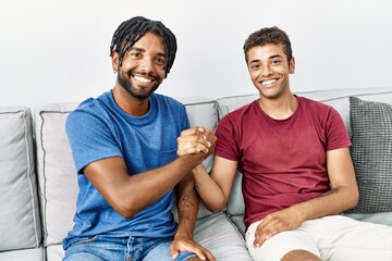 Poster - Two men friends smiling confident shake hands sitting on sofa at home