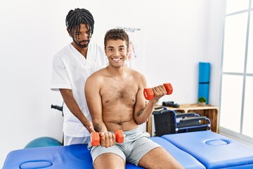 Wall Mural - Two men physiptherapist and patient having rehab session using dumbbell at clinic