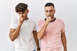 © Krakenimages.com - Young gay couple standing over isolated background feeling unwell and coughing as symptom for cold or bronchitis. health care concept.