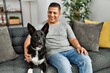 © Krakenimages.com - Young hispanic man smiling happy sitting on the sofa with dog at home.