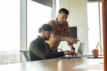 Poster - Two male colleagues working together, discussing business ideas near laptop computer at open space company office
