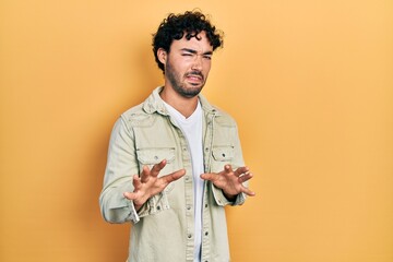 Wall Mural - Young hispanic man wearing casual clothes disgusted expression, displeased and fearful doing disgust face because aversion reaction. with hands raised