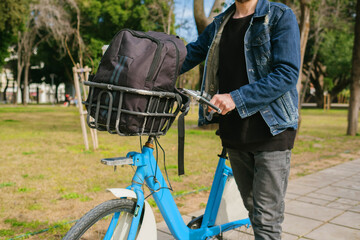 Wall Mural - Bike ride, the young man puts his backpack in the basket of the bike and sets off. It holds the handlebar and is ready to ride. green transportation and green park