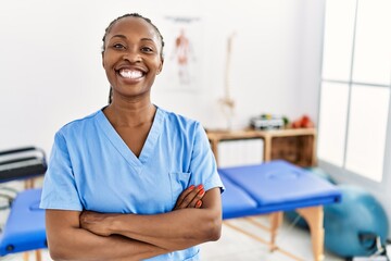 Canvas Print - Black woman with braids working at pain recovery clinic happy face smiling with crossed arms looking at the camera. positive person.