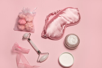 Pink relax face care concept. Silk sleeping mask, white jade facial roller, cream