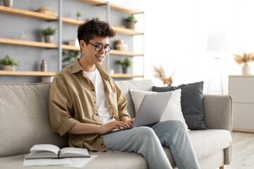 Smiling asian man win glasses orking on laptop at home