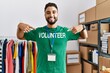 © Krakenimages.com - Young arab man pointing with fingers to volunteer uniform at charity center
