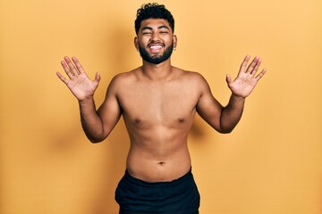 Wall Mural - Arab man with beard wearing swimwear shirtless celebrating crazy and amazed for success with arms raised and open eyes screaming excited. winner concept