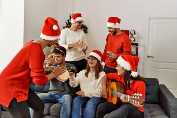 Canvas Print - Group of young people celebrating christmas singing carol song at home.