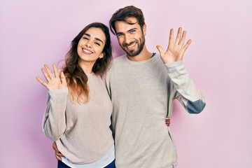 Young hispanic couple wearing casual clothes waiving saying hello happy and smiling, friendly welcome gesture