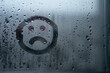 © yaroslav1986 - Sad smiley drawn by hand on wet fogged glass from the rain, copy the space. Concept of loneliness, sadness, bad weather