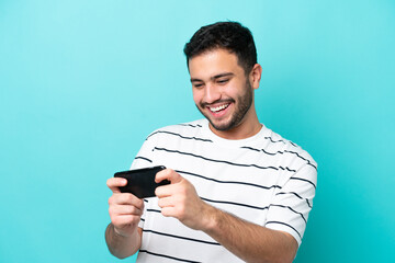 young brazilian man isolated on blue background playing with the mobile phone