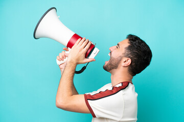 Wall Mural - Young Brazilian man isolated on blue background shouting through a megaphone to announce something in lateral position