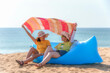 Two woman tourist, sitting on inflatable sofa, enjoy and relax on the beach. Taken picture at the Mai Khao Beach, near Phuket International Airport.