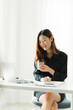 © PaeGAG - Beautiful young asian business woman drinking coffee and using laptop computer while working in office.