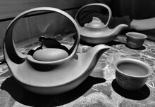 Black-and-white Image Of Two Teapots And Who Cups On The Marble Table.