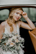 Beautiful bride with a bouquet in a vintage car.