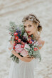 Beautiful bride on a sandy beach. Beautiful wedding bouquet.