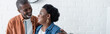 © LIGHTFIELD STUDIOS - happy senior african american man looking at wife in kitchen, banner.