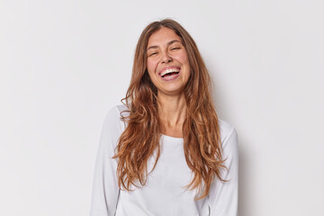 Poster - Positive human emotions concept. Long haired young European woman with piercing smiles toothily dressed in casual jumper isolated over white background. Cheerful female model poses in studio